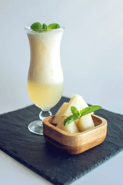 Fresh white smoothie in a glass with sliced pieces of melon and mint on white isolated background. Summer cool drinks — Stock Photo, Image