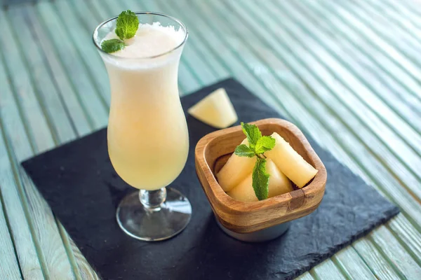 Kavun ve nane bir mavi ahşap zemin üzerine dilimlenmiş parçaları ile bir bardak taze beyaz yüzlü. Yaz soğuk içecekler