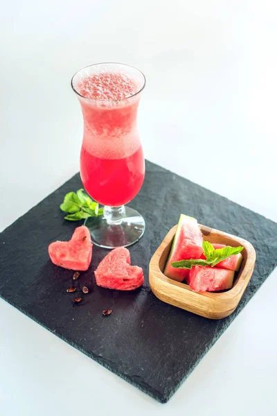 Batido rojo fresco en un vaso con trozos de sandía en rodajas y menta sobre fondo blanco aislado. Bebidas frescas de verano — Foto de Stock