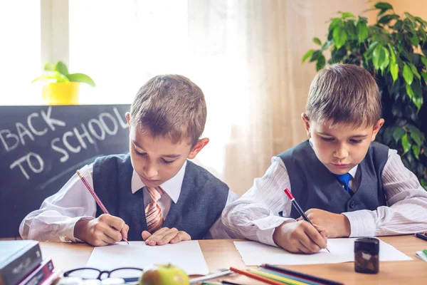 Zurück zur Schule. Nette Kinder, die am Schreibtisch im Klassenzimmer sitzen. Jungen lernen daraus. Konzept Grundschule — Stockfoto