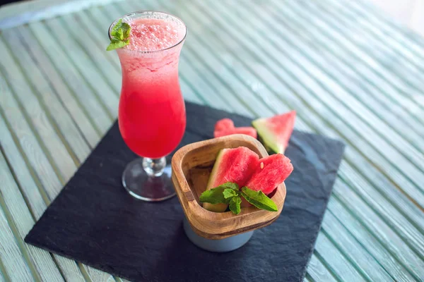 Čerstvé červené smoothie ve sklenici s nakrájené kousky melounu a máty na modrém pozadí dřevěná. Letní studené nápoje — Stock fotografie