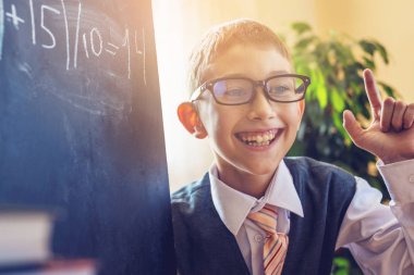 Okula dönüş. Şirin çocuk sınıfta masasında oturuyor. Çocuk keşfetmek bir ders sırasında önemli bilgiler