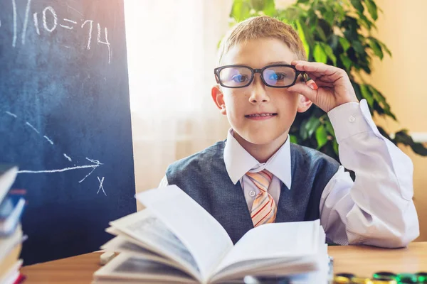 Zurück zur Schule. Nettes Kind, das am Schreibtisch im Klassenzimmer sitzt. Junge liest ein Buch über die Lektion — Stockfoto