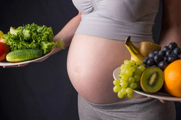 Femme enceinte avec le ventre tenant une assiette avec des fruits et légumes dans les mains. Concept alimentation saine pendant la grossesse — Photo