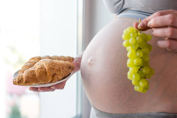 Беременная женщина, держащая тарелку с нездоровой пищей. Концепция выбора диеты во время беременности
