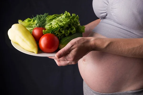 Kobieta w ciąży brzuch gospodarstwa talerz z warzywami. Koncepcja dla kontroli masy ciała i zdrowe odżywianie w ciąży — Zdjęcie stockowe