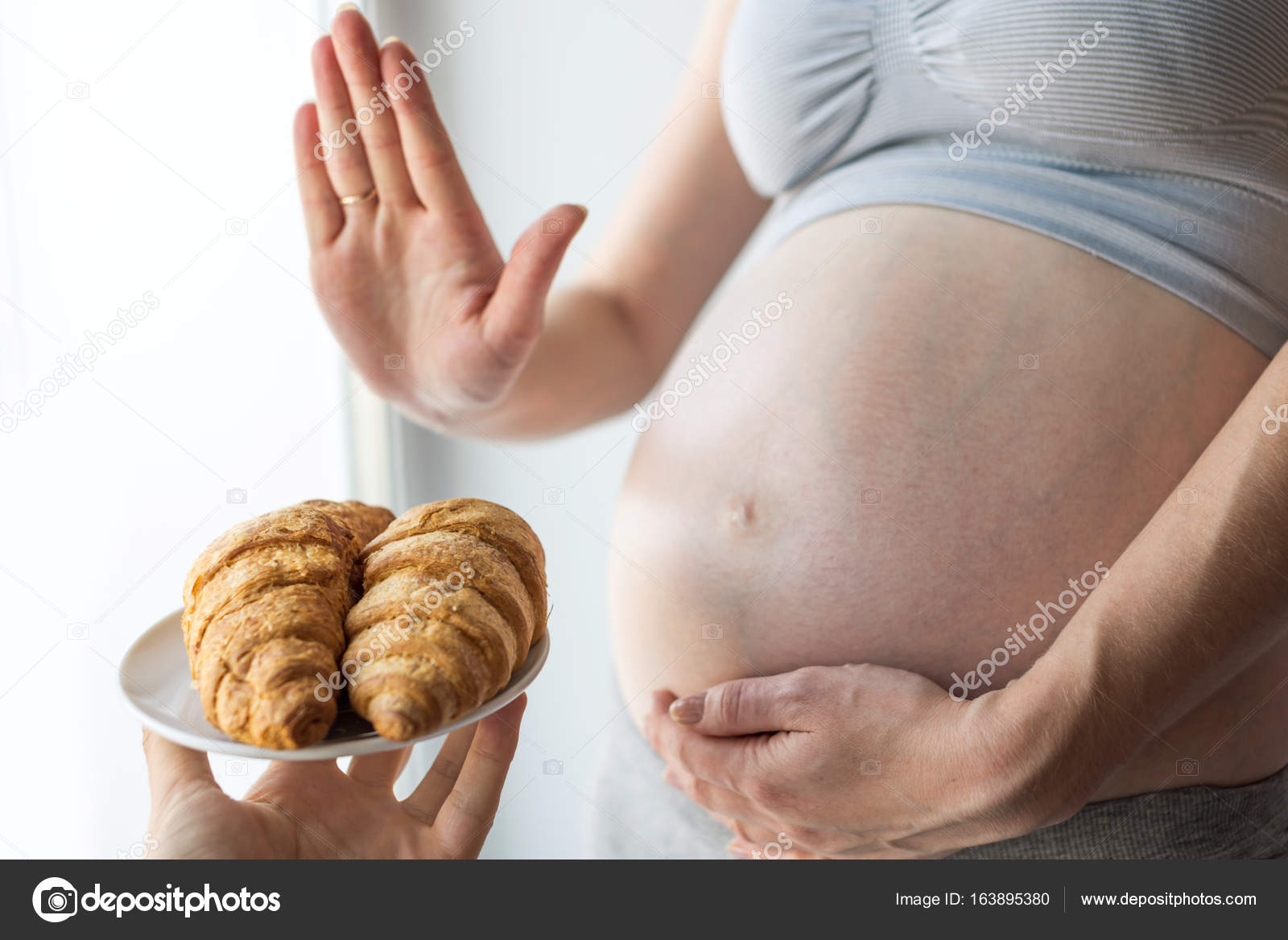 A pregnant woman with belly refuses to croissants. Concept weight ... A pregnant woman with belly refuses to croissants. Concept weight ...