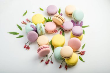 Renkli macarons yaprakları ve beyaz zemin üzerine kırmızı çiçekler ile. Fransız hassas tatlı