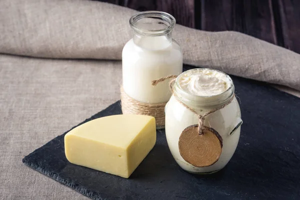 Eko çiftlik ürünleri süt, peynir, ekşi krema, koyu ahşap zemin üzerine yoğurt. Ev yapımı doğal gıda kavramı