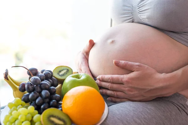 Egy terhes nő hasa tartja a házunkba, gyümölcskosár. Koncepció súlykontroll és az egészséges táplálkozás a terhesség alatt — Stock Fotó