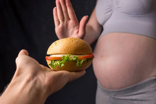 Έγκυος γυναίκα με κοιλιά αρνείται από το burger. Ο έλεγχος έννοιας κατά τη διάρκεια του βάρους εγκυμοσύνης — Φωτογραφία Αρχείου