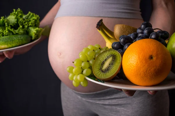 Donna incinta con pancia che tiene un piatto con frutta e verdura in mano. Concetto alimentazione sana durante la gravidanza — Foto Stock