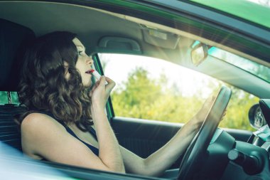 Sürücü kadın ayna ve araba ruj arıyorum. Dalgın ve tehlikeli sürüş. Trafik ihlali