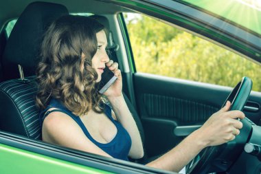 Arabada bir telefonda konuşurken kadını sürücüsü. Dalgın ve tehlikeli sürüş. Trafik ihlali.