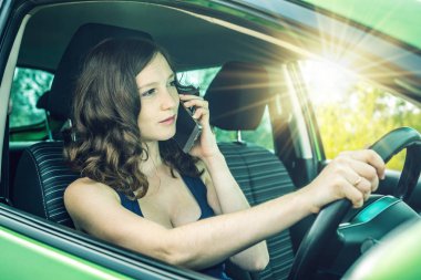 Arabada bir telefonda konuşurken kadını sürücüsü. Dalgın ve tehlikeli sürüş. Trafik ihlali.