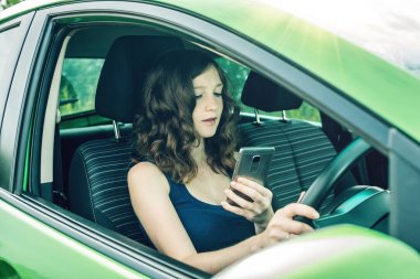 Sürücü kadın arabada telefon bakarak. Dalgın ve tehlikeli sürüş. Trafik ihlali.