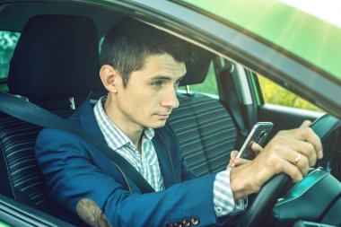 Sürücü adam telefonu arabada bakarak. Dalgın ve tehlikeli sürüş. Trafik ihlali.