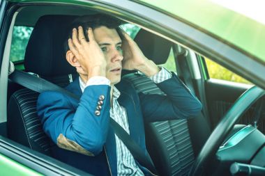 Kafasını tutarak arabada oturan adam sürücü. Yolda ve tehlikeli sürüş kaza kavramı