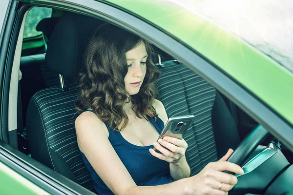 Sürücü kadın arabada telefon bakarak. Dalgın ve tehlikeli sürüş. Trafik ihlali.