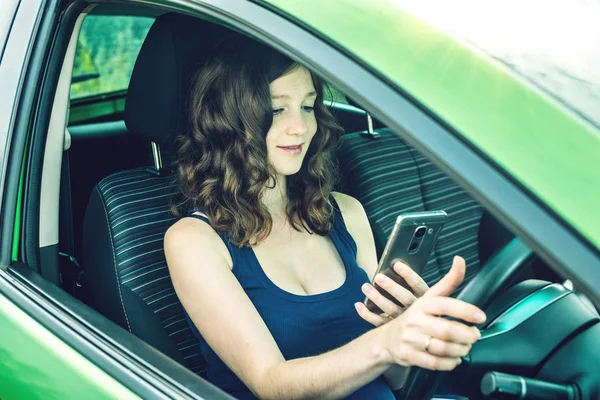 Sürücü kadın arabada telefon bakarak. Dalgın ve tehlikeli sürüş. Trafik ihlali.