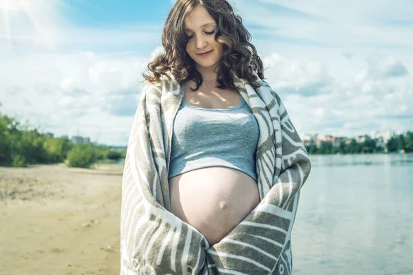 Schwangere spazieren am Ufer des Flusses. In eine Decke gehüllt — Stockfoto