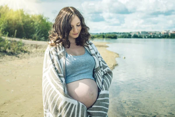 Schwangere spazieren am Ufer des Flusses. In eine Decke gehüllt — Stockfoto