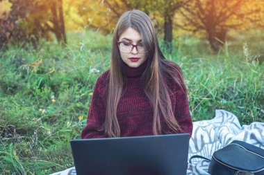 Çalışma veya dizüstü kablosuz yazdırma metin üzerinde eğitim kadın. Sonbahar Park. Kavramını eğitim ve doğa ile çalışma