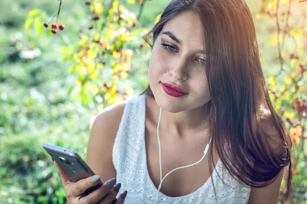 Kobieta, słuchanie muzyki w telefonie, noszenie słuchawek w słoneczny dzień. Koncepcja kształcenia Audiobooki, student — Zdjęcie stockowe