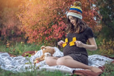 Bir mide ile bekleyen anne battaniye üzerinde oturur ve bebeğe anlatır. Gebelik ve sonbahar uyum kavramı