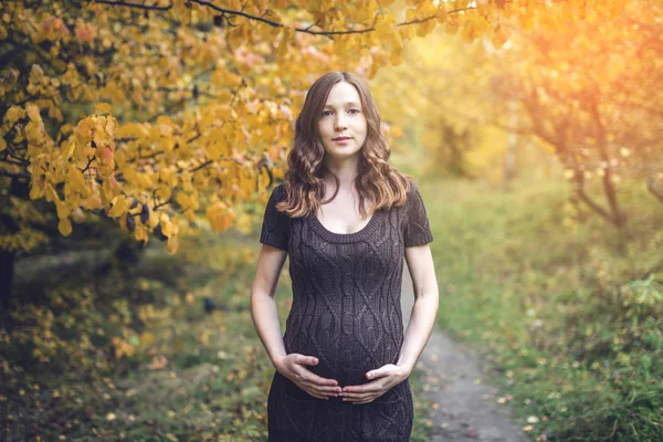 Ritratto di donna incinta pancia nella colorata foresta autunnale nel mese di settembre. Concetto di gravidanza e le stagioni — Foto Stock