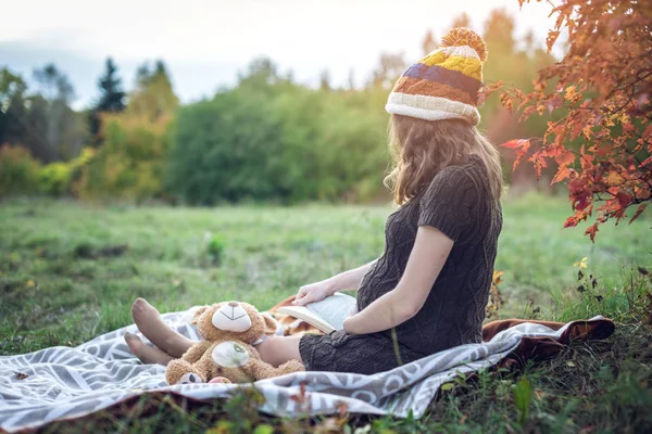 Donna incinta con una pancia che legge storie al bambino. Concetto di gravidanza e l'armonia di autunno — Foto Stock