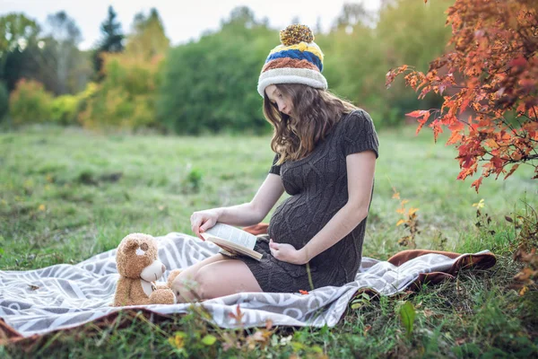 Donna incinta con una pancia che legge storie al bambino. Concetto di gravidanza e l'armonia di autunno — Foto Stock