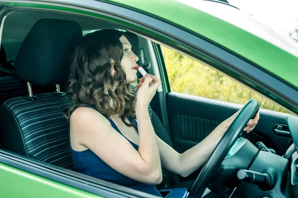 Sürücü kadın ayna ve araba ruj arıyorum. Dalgın ve tehlikeli sürüş. Trafik ihlali