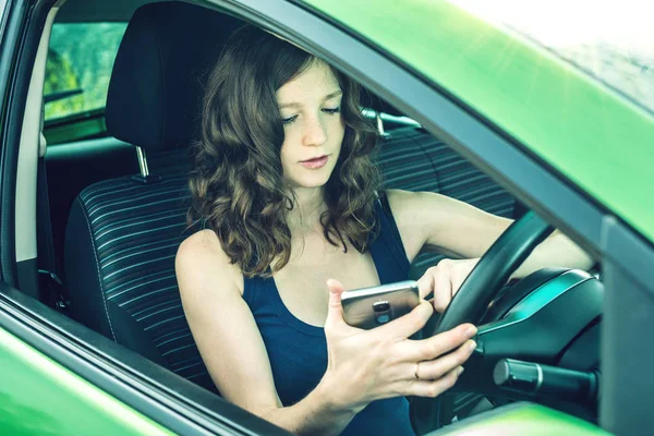 Řidič ženy při pohledu na telefon v autě. Roztržitý a nebezpečné jízdy. Dopravní přestupky. — Stock fotografie