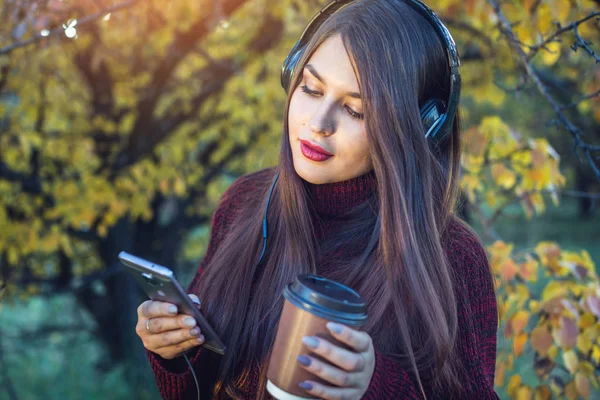 Kobieta jesień Park, słuchanie muzyki z jej telefonu i słuchawki. Pojęcie dobrego nastroju, ulubionej muzyki, szczęśliwy czas. — Zdjęcie stockowe