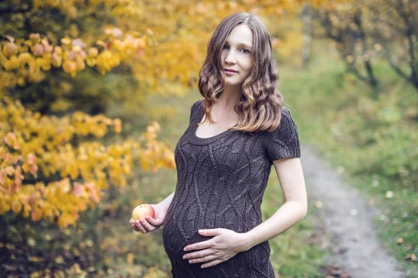 Portret kobiety w ciąży brzuch w kolorowe jesień las we wrześniu. Koncepcja ciąży i pory roku — Zdjęcie stockowe