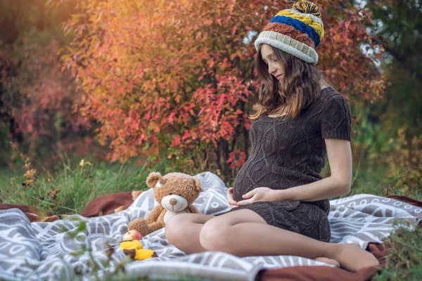 Bir mide ile bekleyen anne battaniye üzerinde oturur ve bebeğe anlatır. Gebelik ve sonbahar uyum kavramı — Stok fotoğraf