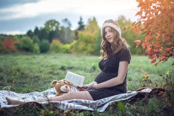 Zwangere vrouw met een buik die het lezen van verhalen aan de baby. Concept van de zwangerschap en de herfst harmonie — Stockfoto