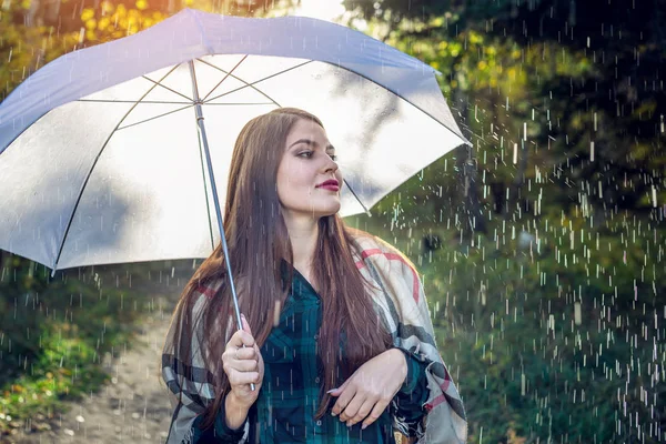 雨の中白い傘と日当たりの良い公園を歩いて幸せな若い女。季節と秋の気分のコンセプト — ストック写真