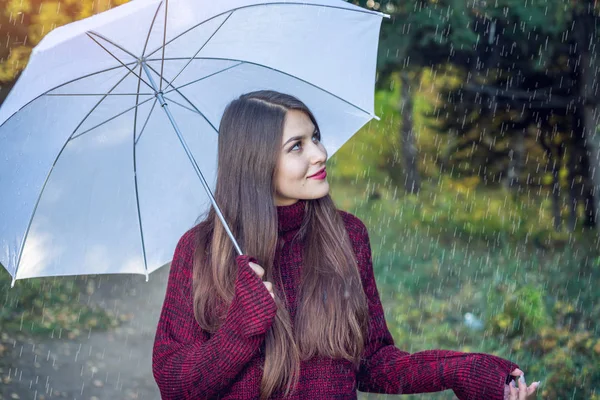 Feliz joven caminando en un Sunny Park con un paraguas blanco bajo la lluvia. Concepto de estaciones y estado de ánimo de otoño — Foto de Stock