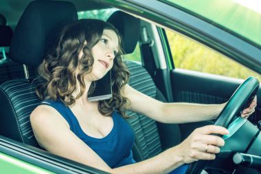 Arabada bir telefonda konuşurken kadını sürücüsü. Dalgın ve tehlikeli sürüş. Trafik ihlali.