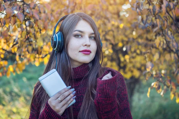 Kobieta jesień Park, słuchanie muzyki z jej telefonu i słuchawki. Pojęcie dobrego nastroju, ulubionej muzyki, szczęśliwy czas. — Zdjęcie stockowe