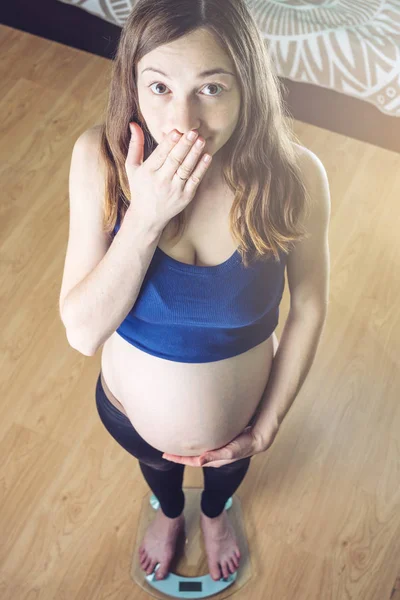 Femme enceinte debout sur des balances dans la chambre. Concept de perte de poids et de contrôle pendant la grossesse — Photo