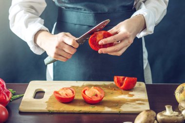 Siyah önlük Şef domates kes. Yemek pişirmek için çevre dostu ürünler kavramı