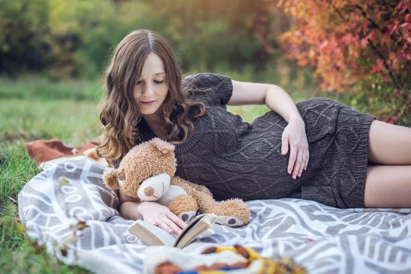Bir battaniye ve bebeğe hikayelerini okuyarak bir karın hamile kadınla yatıyor. Gebelik ve sonbahar uyum kavramı — Stok fotoğraf