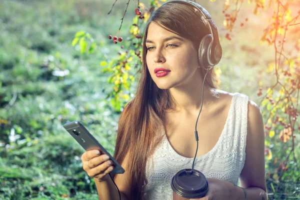 Kobieta, słuchanie muzyki w telefonie, noszenie słuchawek w słoneczny dzień. Koncepcja kształcenia Audiobooki, student — Zdjęcie stockowe