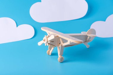 Ahşap oyuncak uçak arka plan mavi gökyüzü ile kağıt bulutlar üzerinde. Kavram seyahat ve hava yolları