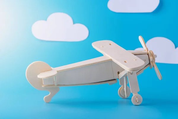 Wooden toy airplane on a background of blue sky with paper clouds. Concept travel and airlines