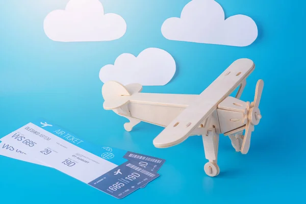 Wooden toy airplane and tickets on a background of blue sky with paper clouds. Concept travel and airlines