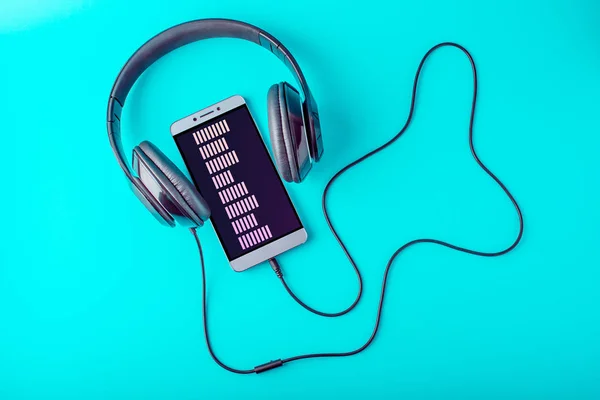 Еквалайзер на екрані телефону з навушниками, що грають музику на синьому фоні — стокове фото